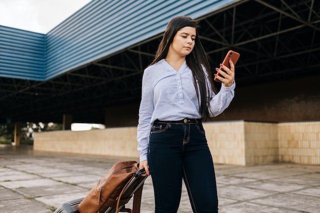 traveler woman walking at station with suitcase and cellphone