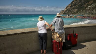 man-and-woman-standing-beside-concrete-seawall-looking-at-beach